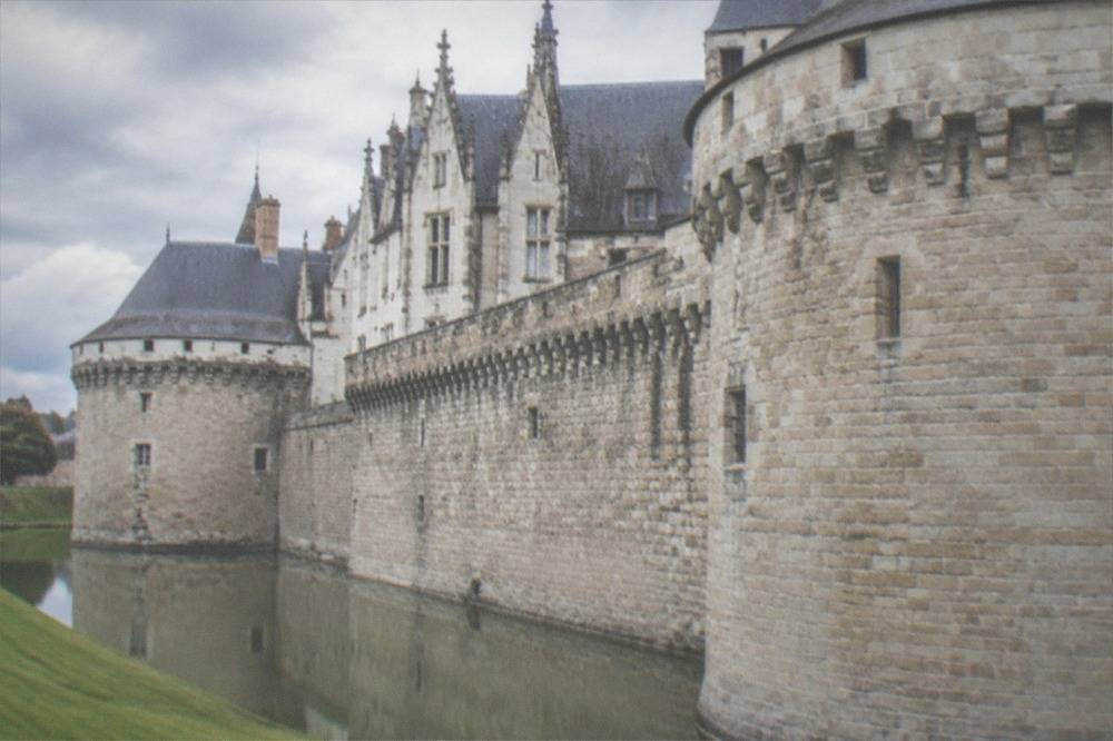 The stone ramparts and grassy moat of the Château des ducs de Bretagne on a bright day