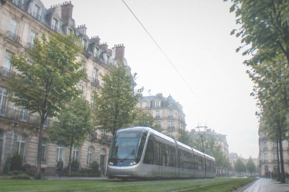 A modern tram moving along a grassed track through a Nantes street