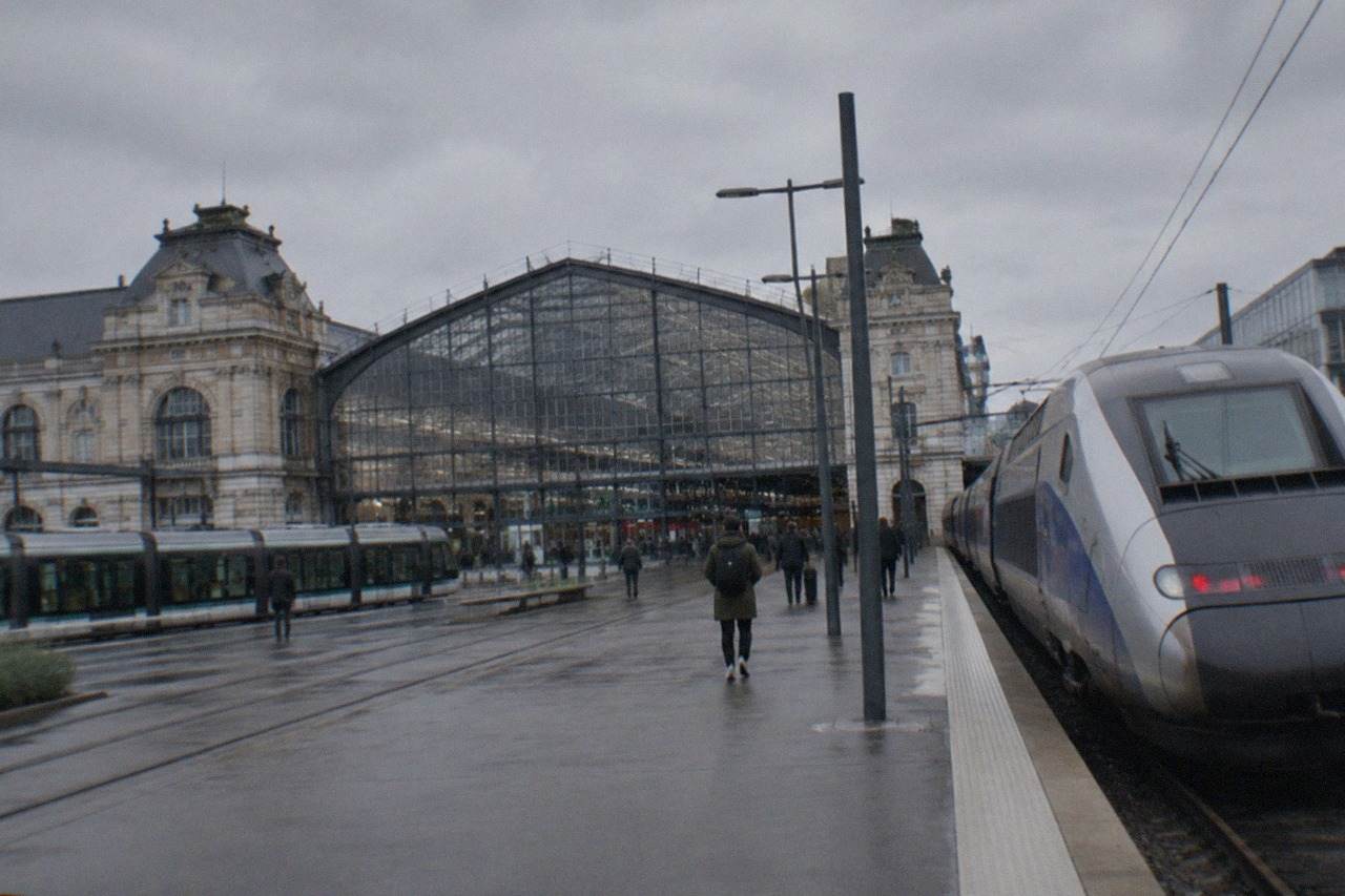 A high speed train standing at a station platform beside a modern glass station facade