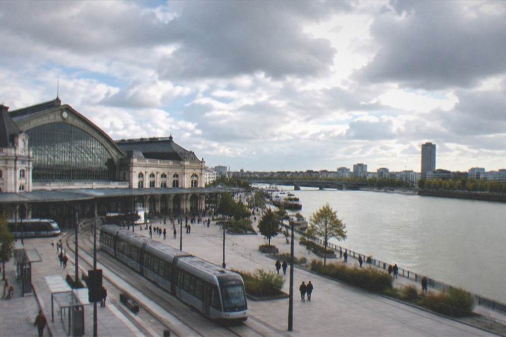 A wide river flowing past a modern city skyline with a distant tower
