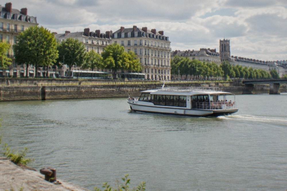 A river shuttle boat crossing the Loire between Nantes quays on a summer morning