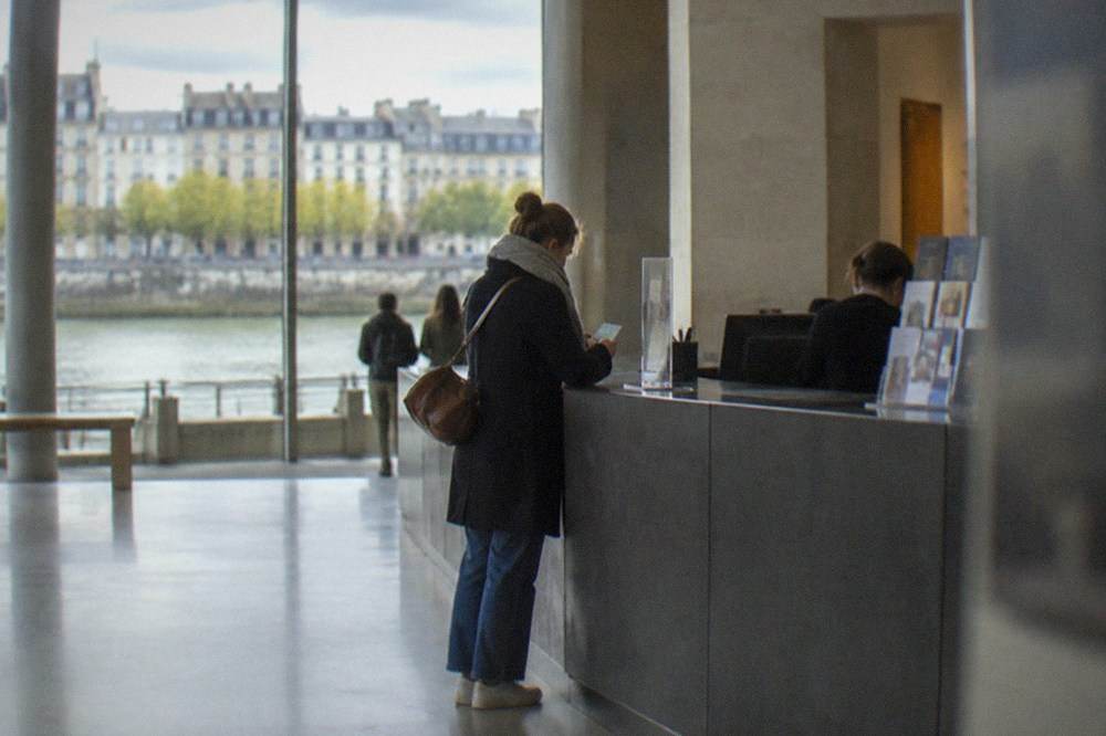 A museum ticket desk in Nantes with a visitor checking a city pass and map