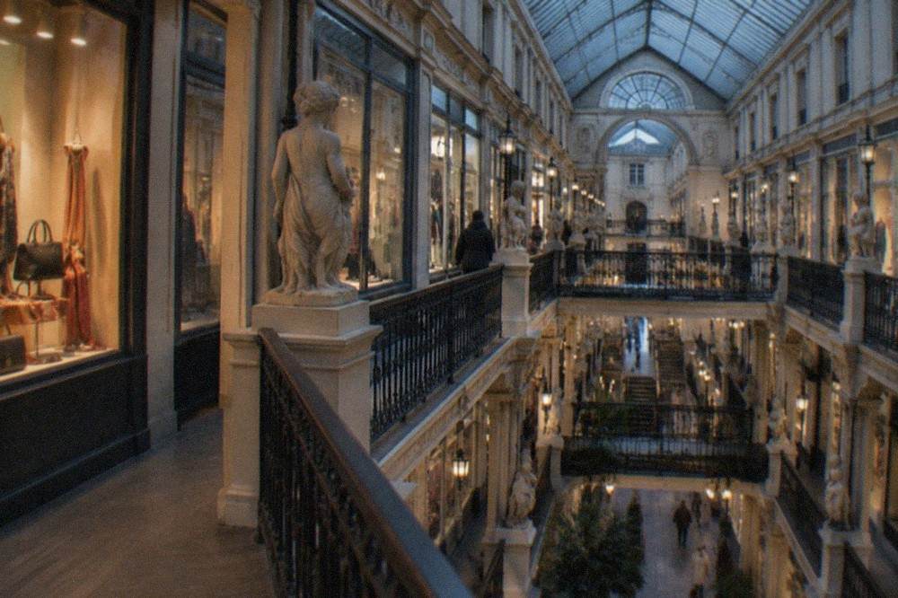 A boutique window display with handbags and scarves lit from above in a nineteenth-century arcade