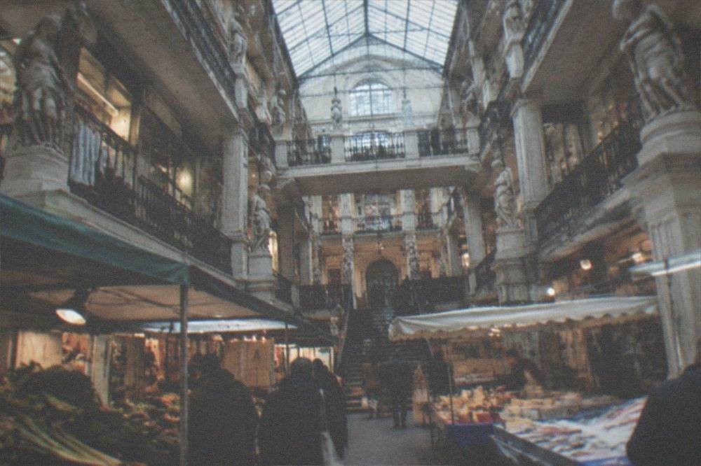 A covered market hall with stalls of vegetables, cheese and fish in the morning