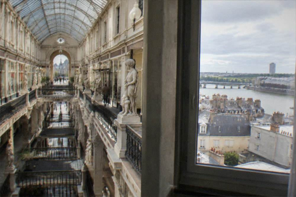 A hotel room window looking out over city rooftops towards a river