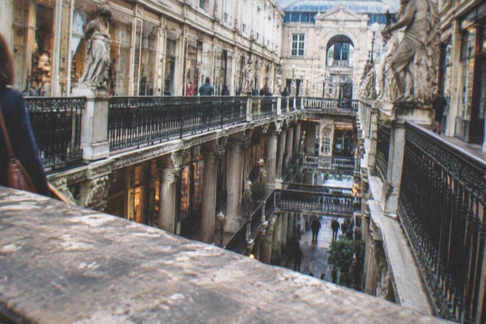A historic apartment building facade with iron balconies above a shopping street