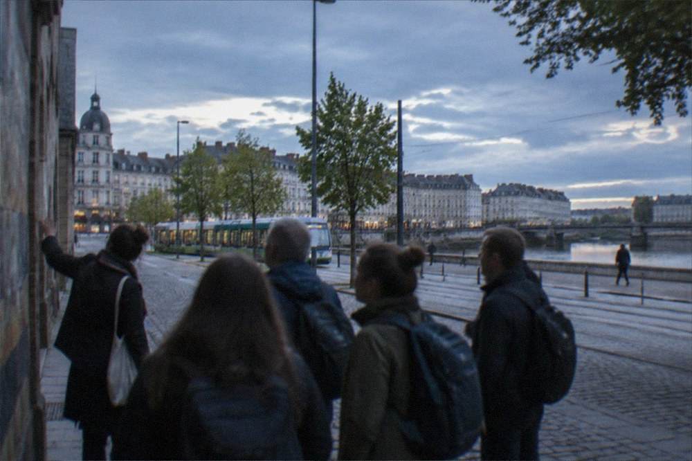 A small group with a guide stopping at a painted wall in an old-town street in Nantes