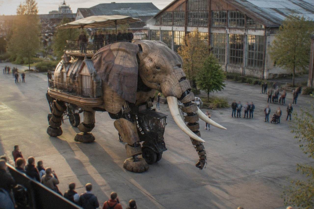 A mechanical elephant walking past converted warehouses on the Ile de Nantes