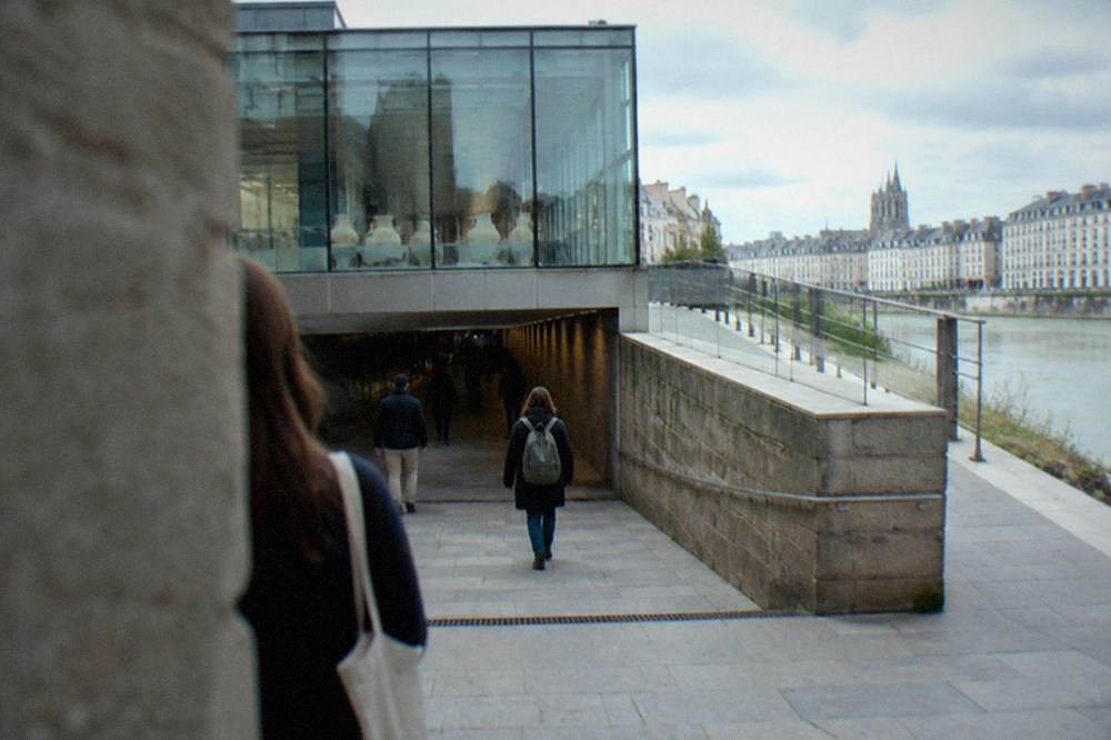 Visitors walking through the dim underground passage of a riverside memorial
