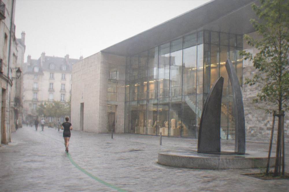 A green painted trail line leading past a contemporary public sculpture in a French city square