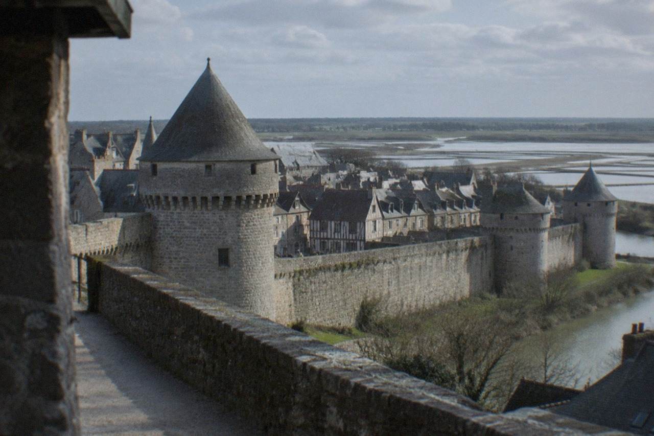The stone ramparts and rooftops of Guerande medieval town in western France under a clear sky