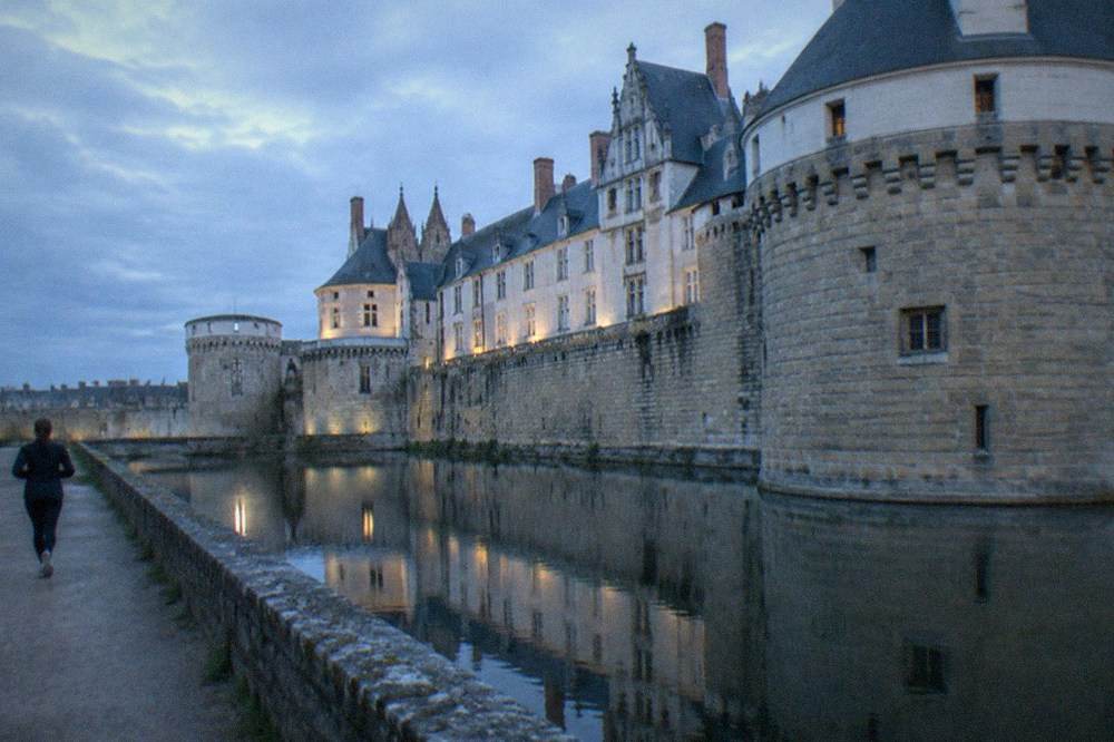 The ramparts of the Château des ducs de Bretagne in Nantes reflected in the moat at dusk