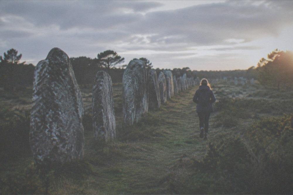 Ancient granite standing stones of the Carnac alignments stretching across a Brittany field