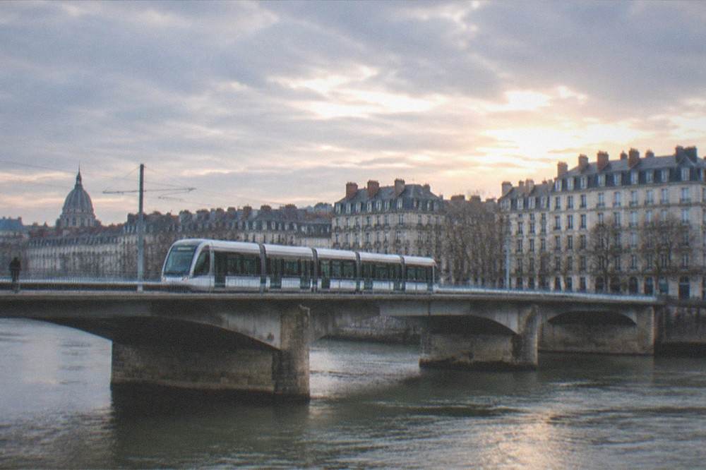 A modern Nantes tram crossing one of the city bridges over the Loire in evening light