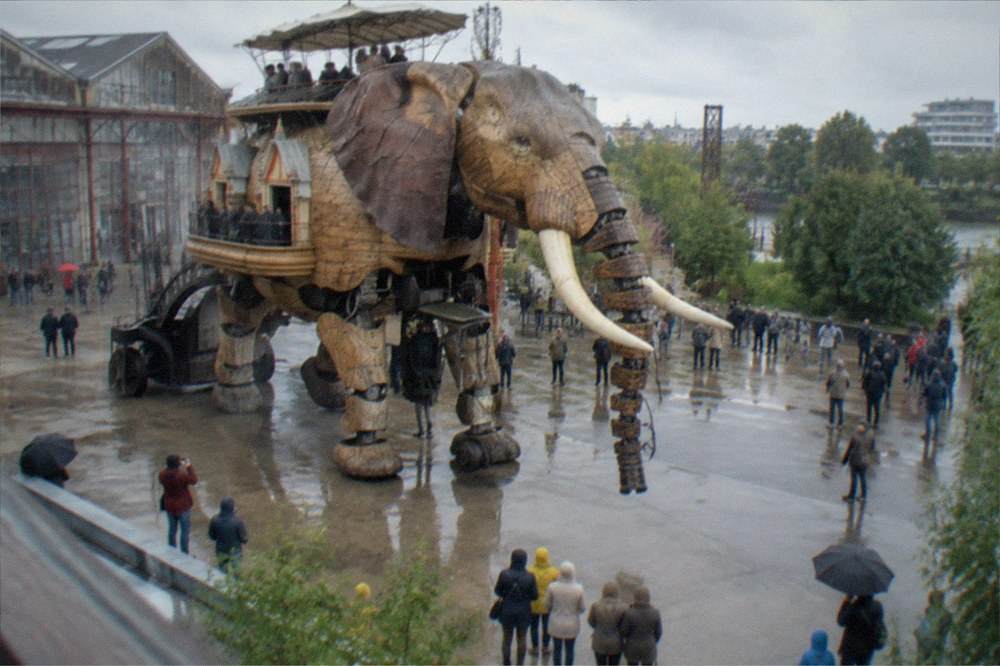 The mechanical elephant of the Machines de l'île walking past visitors on the Île de Nantes