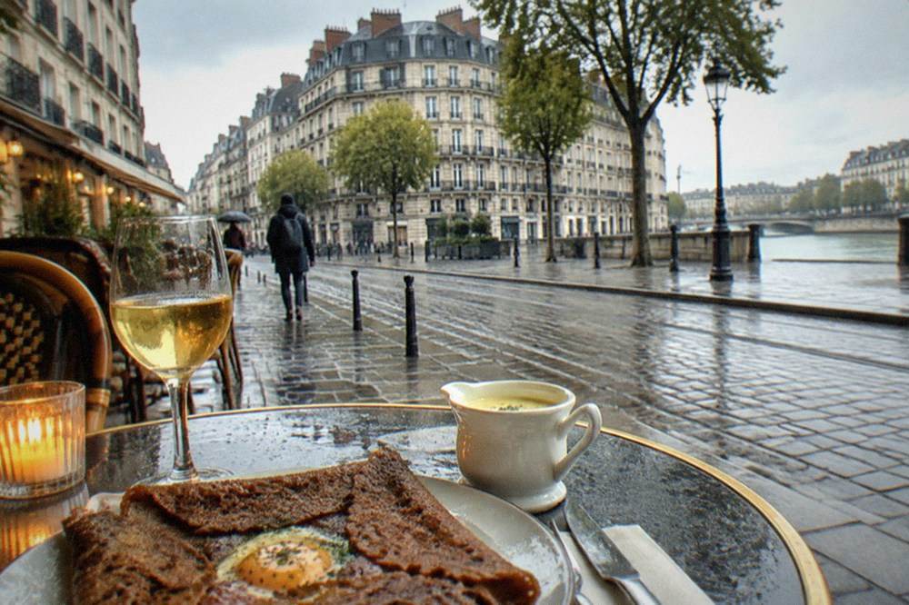 A candlelit bistro table with a galette, white wine and a small jug of beurre blanc sauce on a Nantes lane
