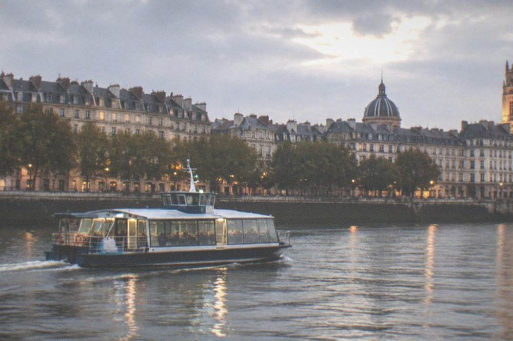 A Navibus ferry crossing the Loire at dusk with the lit towers of Nantes on the far bank