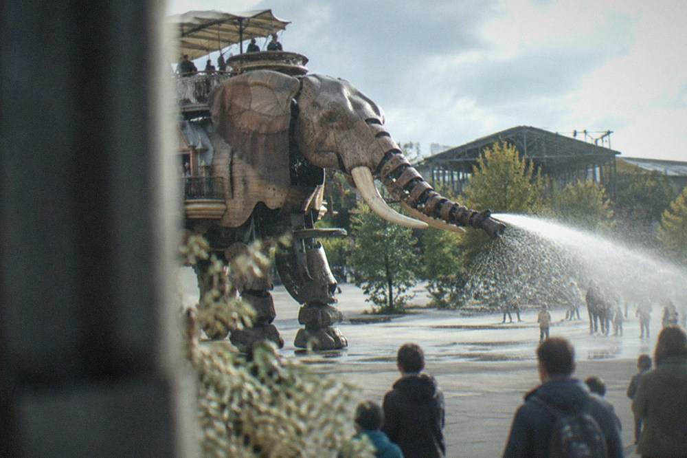 The mechanical Grand Éléphant of Les Machines de l'île spraying water near visitors on the Île de Nantes
