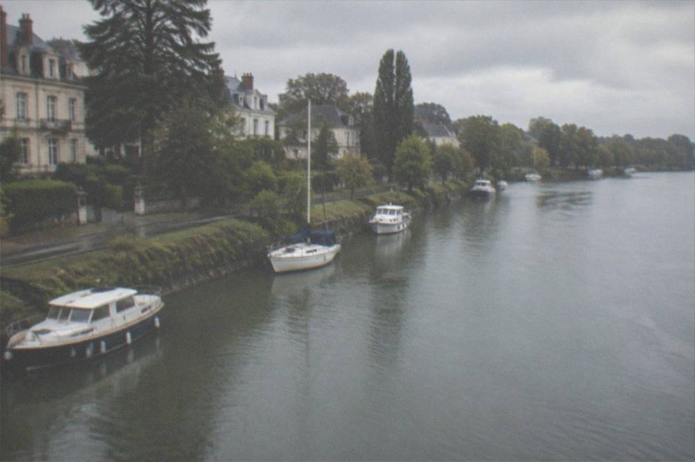Boats moored along the tree-lined Erdre river in Nantes in late afternoon light