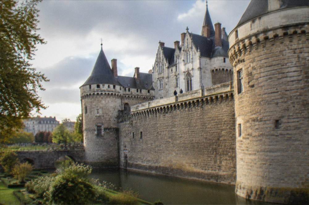 The rampart walk of the Château des ducs de Bretagne seen from below, with the castle walls rising over the moat garden