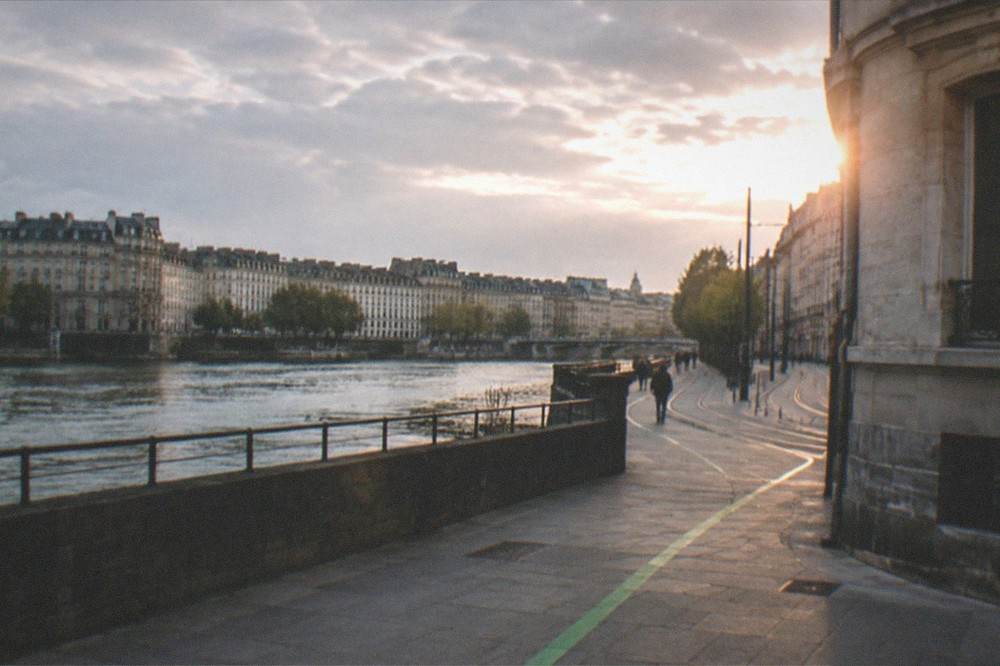 A green painted line on a Nantes pavement leading past a street corner in the evening