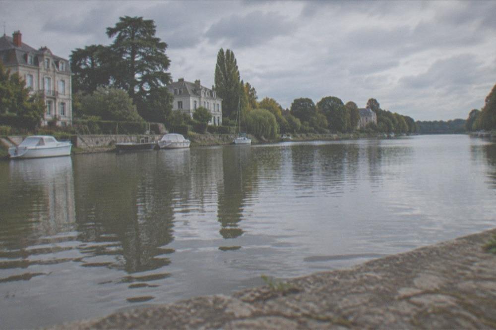 Tree-lined banks of the Erdre river with small boats moored along the water