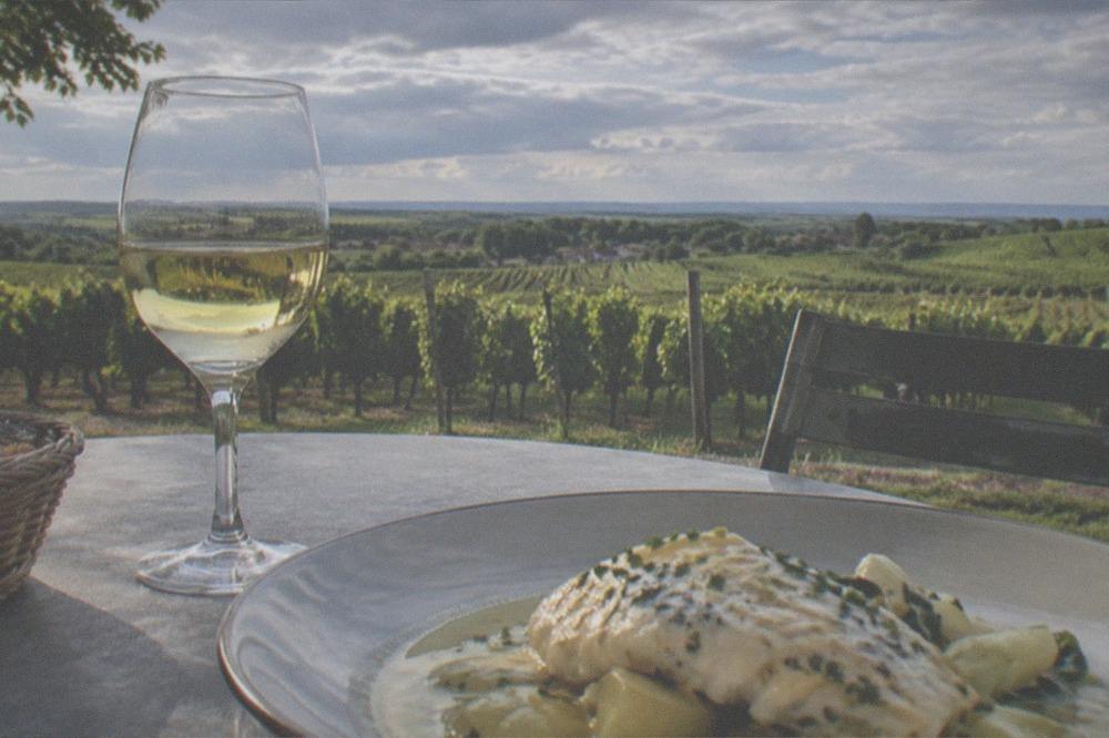 A bistro table with a glass of white Muscadet wine and a fish dish in beurre blanc sauce