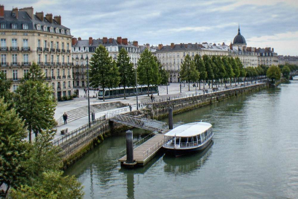 A small covered ferry moored at a wooden pontoon on the Erdre