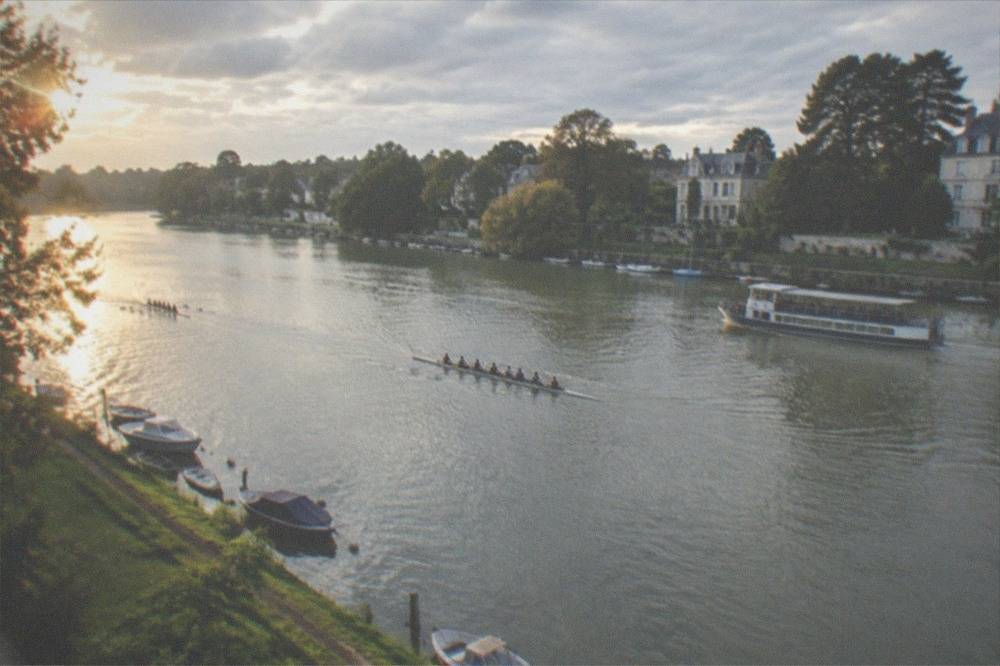 Rowing boats and a passenger vessel on the Erdre on a bright afternoon