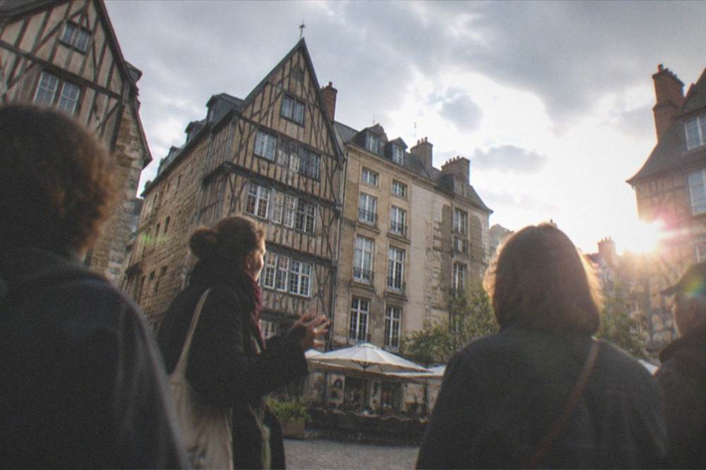 A guide speaking to a small group of visitors in a historic city square