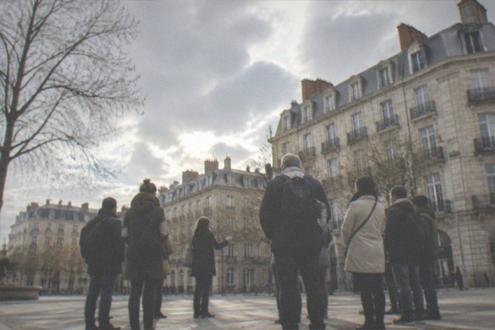 A small guided walking group listening to a guide in a Nantes square